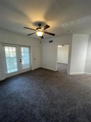 an empty room with a chandelier fan and windows