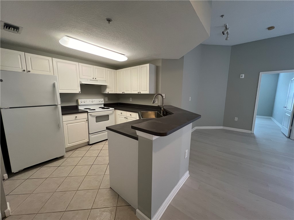 5090 Fairways Circle, Unit H308 Vero Beach, FL 32967 - Photo 2 of 19 a kitchen with a sink a refrigerator a microwave and cabinets