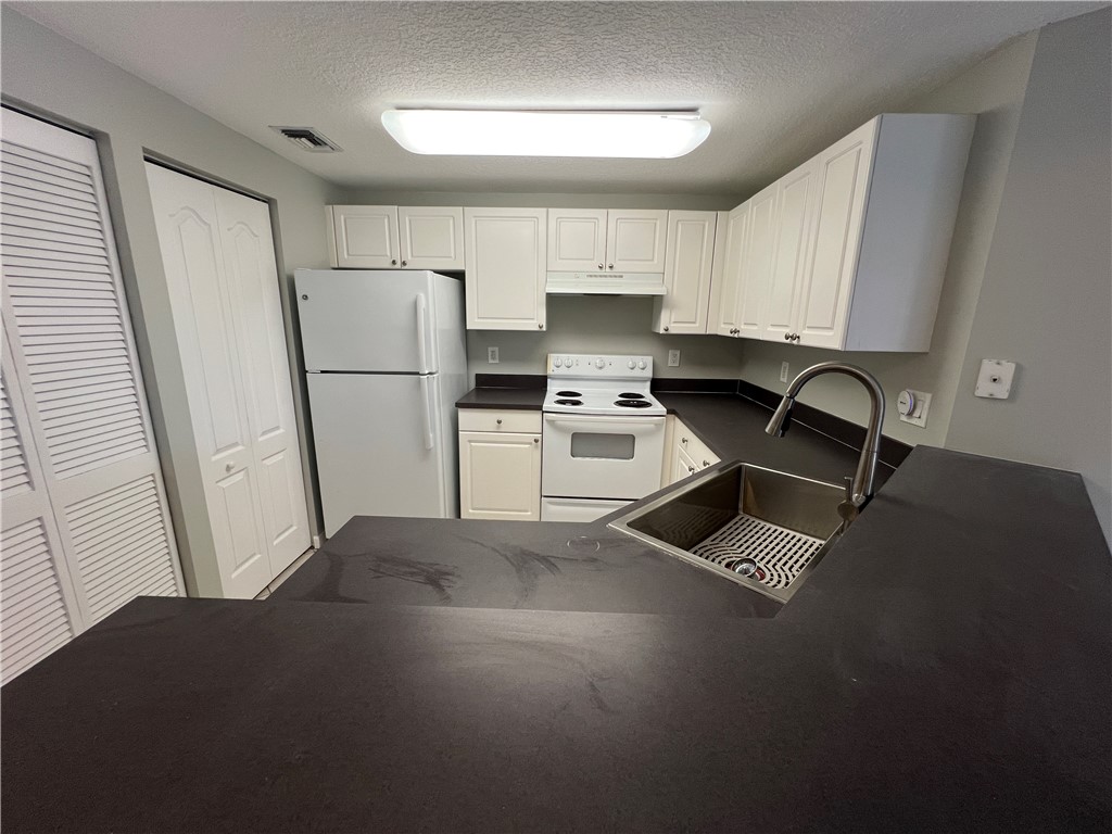 5090 Fairways Circle, Unit H308 Vero Beach, FL 32967 - Photo 3 of 19 a kitchen with a refrigerator a stove a sink dishwasher and a stove with wooden floor