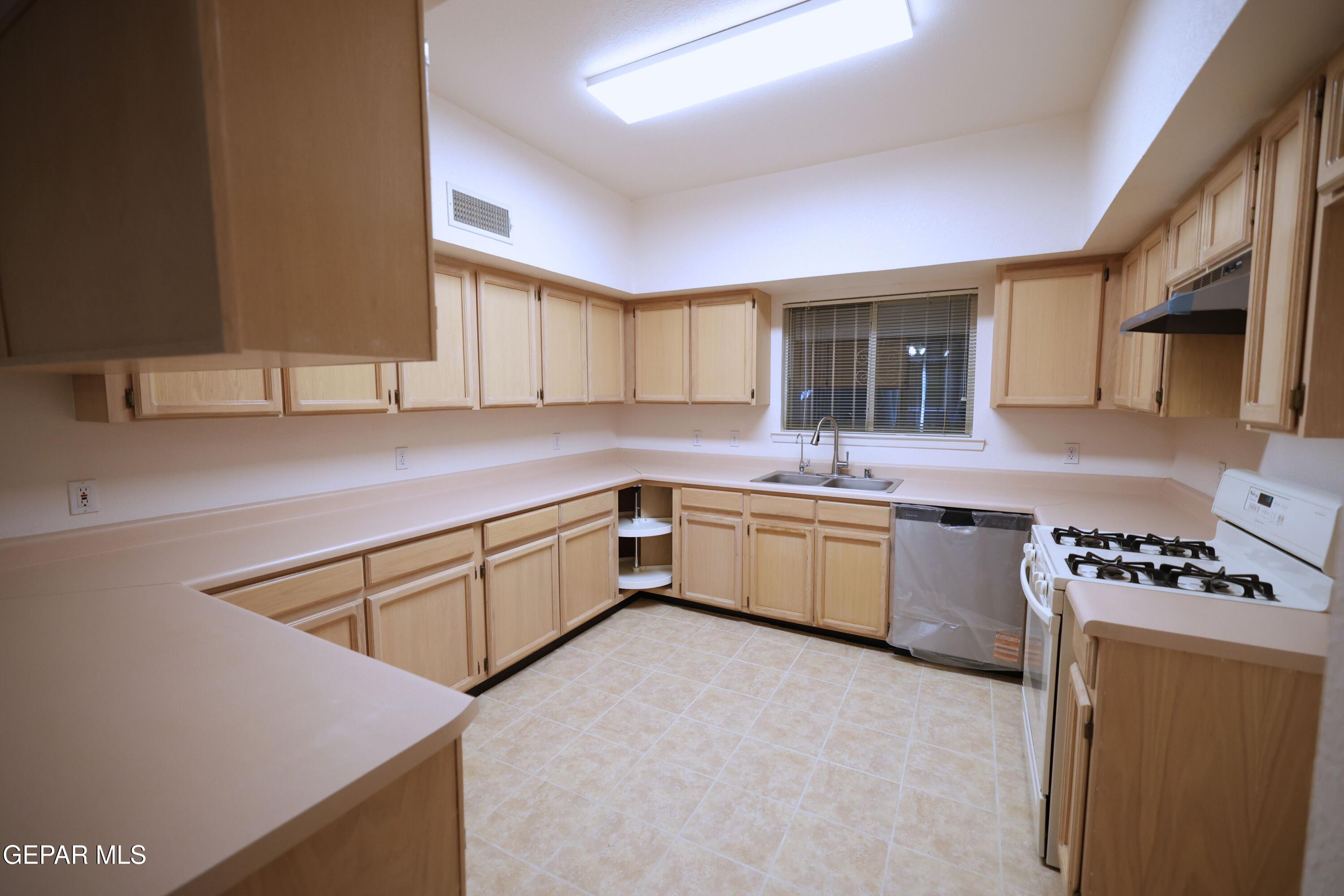 2210 Radford Street El Paso, TX 79903 - Photo 5 of 24 a kitchen with stainless steel appliances a sink dishwasher a stove top oven a refrigerator with wooden cabinets and floor