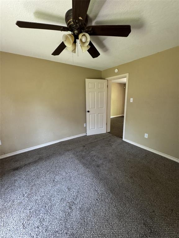 803 Ripley Avenue Ennis, TX 75119 - Photo 18 of 40 Spacious room featuring neutral-toned walls, gray carpet, a white ceiling, white baseboards, and a dark-toned ceiling fan with integrated lighting