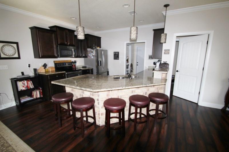 4556 Hermosa Road Crestview, FL 32539 - Photo 7 of 35 a kitchen with stainless steel appliances granite countertop a refrigerator a stove a sink a dining table and chairs with wooden floor