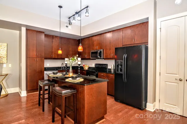 a kitchen with a refrigerator a stove top oven a dining table and chairs