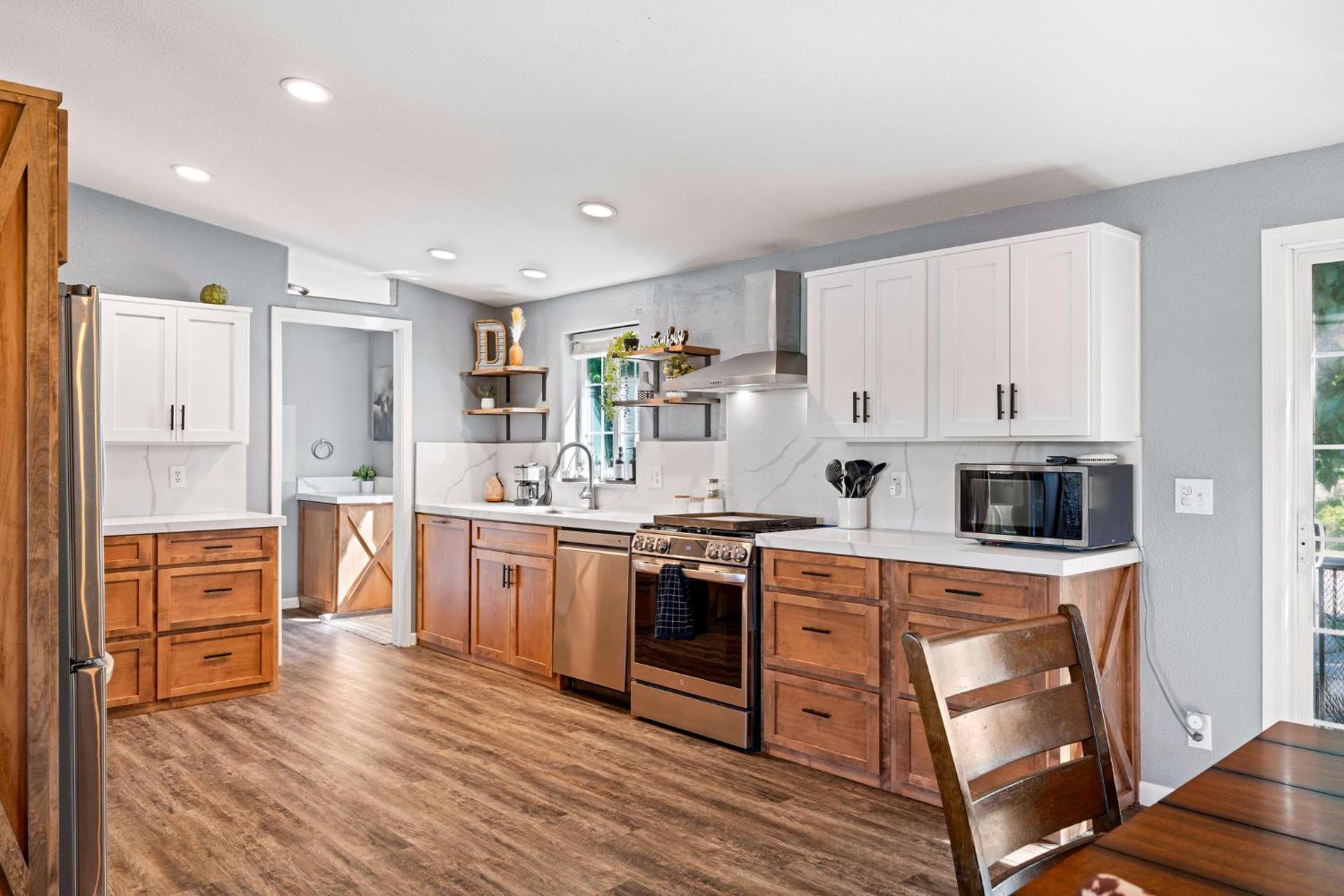 12518 Lone Oak Road Waterford, CA 95386 - Photo 16 of 50 a kitchen with stainless steel appliances granite countertop a stove top oven a sink dishwasher and a refrigerator with wooden floor
