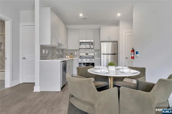a kitchen with stainless steel appliances kitchen island granite countertop a table chairs microwave and cabinets