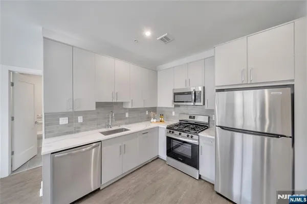 a kitchen with white cabinets sink and refrigerator