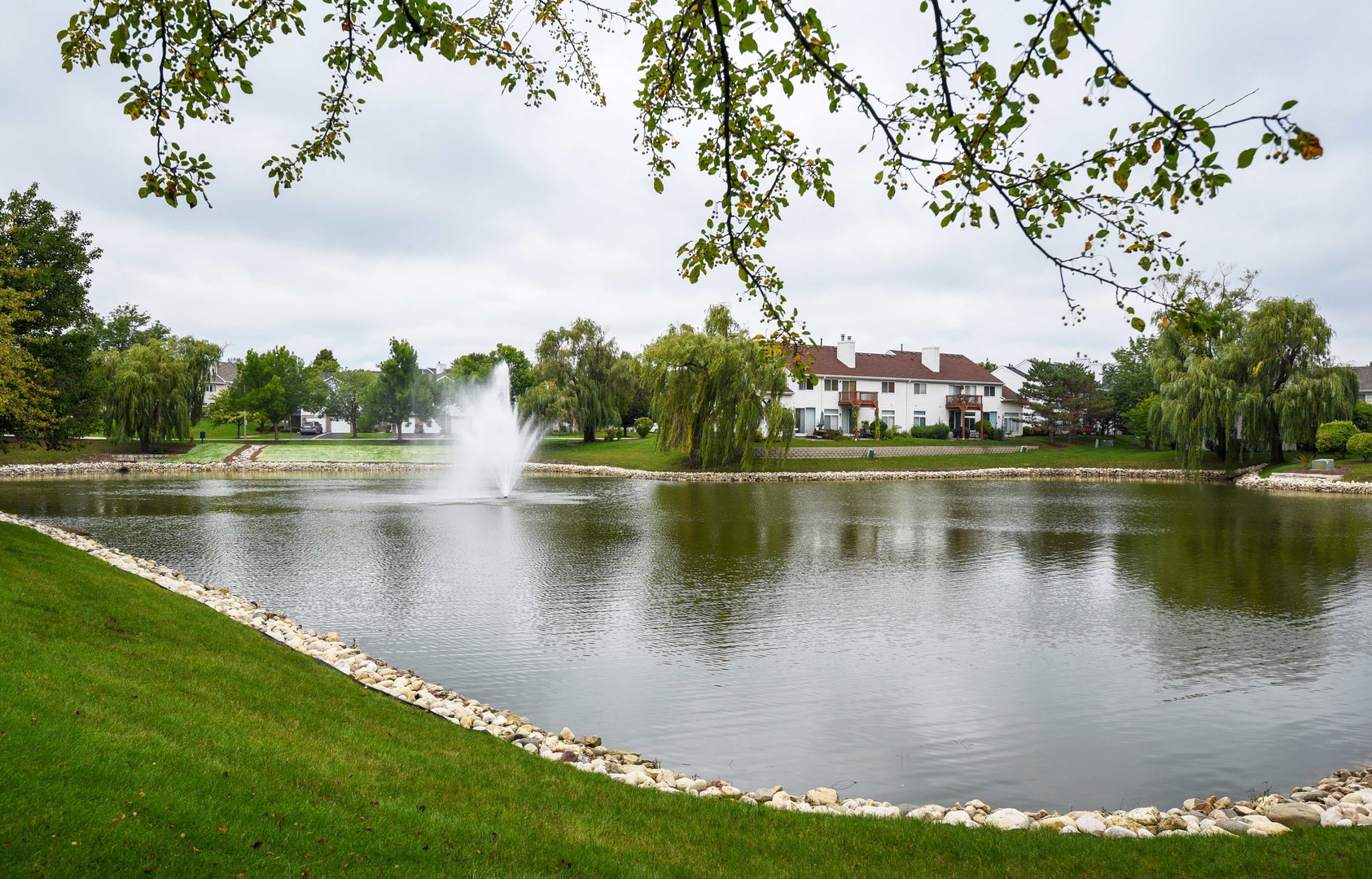 1032 Ripple Ridge, Unit 19 Darien, IL 60561 - Photo 2 of 28 a view of a lake with a yard and trees in the background