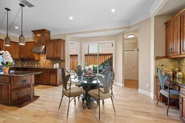 a kitchen with stainless steel appliances granite countertop a stove top oven a sink a dining table and chairs with wooden floor