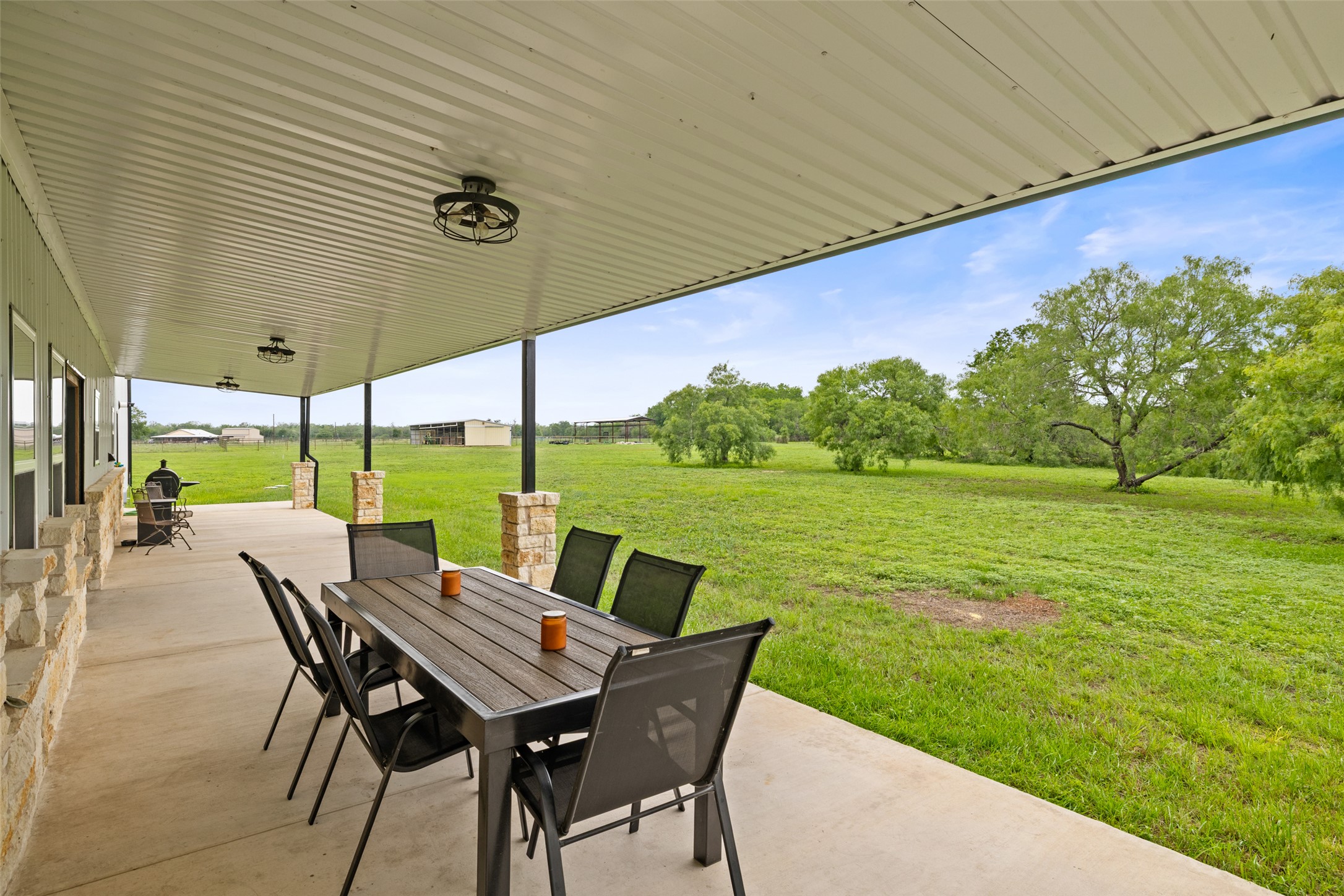664 Martindale Falls Road Martindale, TX 78655 - Photo 17 of 21 Expansive covered patio featuring a concrete surface, stone-clad support columns, and multiple ceiling-mounted light fixtures