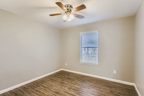 a view of an empty room with window and a chandelier fan