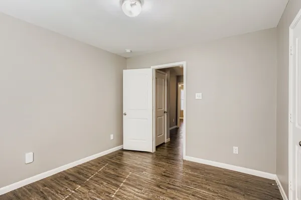 a view of an empty room with wooden floor and closet