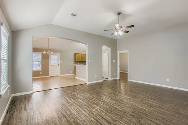 a view of an empty room with window and wooden floor