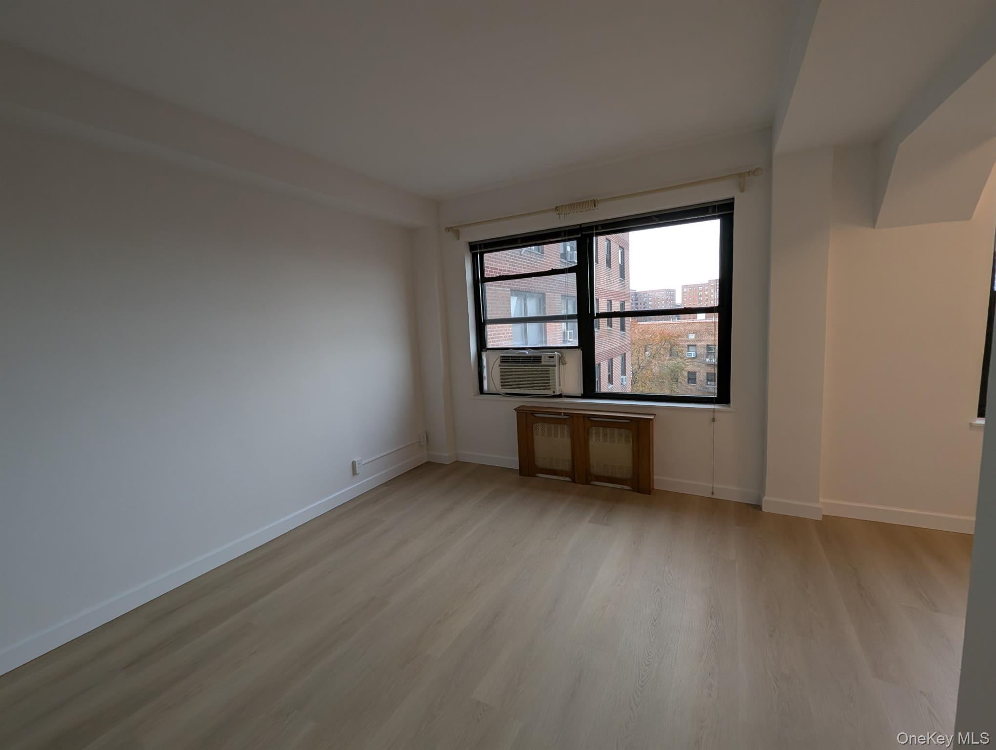 64-34 102nd Street, Unit 7F Queens, NY 11374 - Photo 9 of 17 an empty room with wooden floor and windows