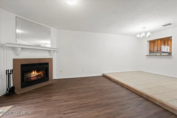 a view of an empty room with a fireplace and wooden floor