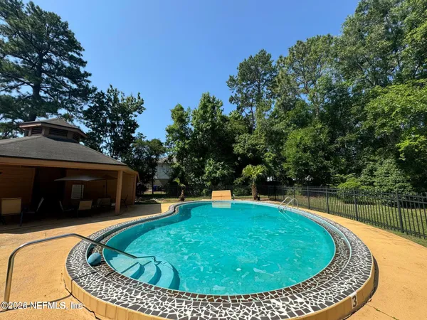 a view of a swimming pool with a garden and trees in the background