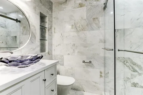 a bathroom with a granite countertop sink a toilet and shower
