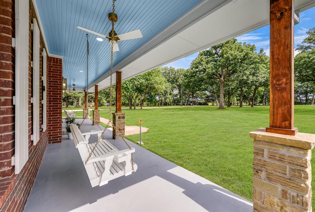 1037 Harrison Road Denison, TX 75021 - Photo 1 of 39 Expansive covered front porch featuring a blue beadboard ceiling, red brick exterior, stone-clad pillars with wood posts, and a ceiling fan