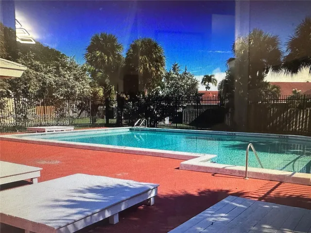 a view of a swimming pool with a yard and palm trees