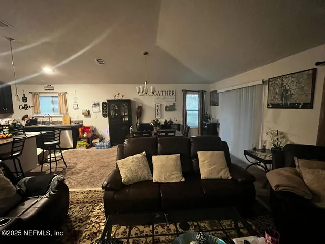 a living room with furniture kitchen view and a window