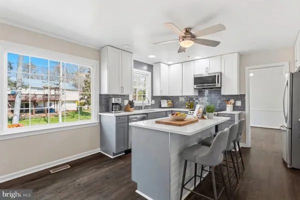 a kitchen with kitchen island a sink cabinets a refrigerator and a window