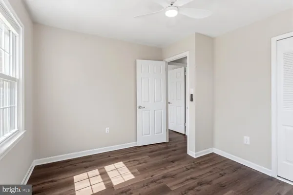 an empty room with wooden floor chandelier fan and windows