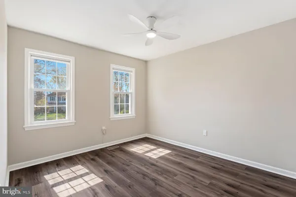an empty room with wooden floor chandelier fan and windows