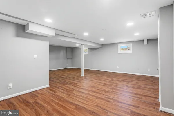 a view of an empty room with wooden floor and a ceiling fan