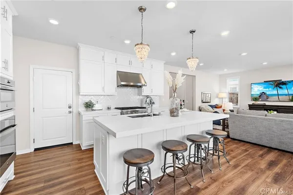 a large kitchen with granite countertop a stove a sink a dining table and chairs with wooden floor