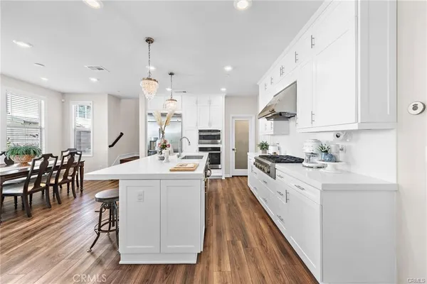 a large kitchen with kitchen island granite countertop lots of white cabinets appliances and furniture