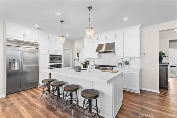 a kitchen with stainless steel appliances granite countertop a sink a stove a refrigerator and island with wooden floor