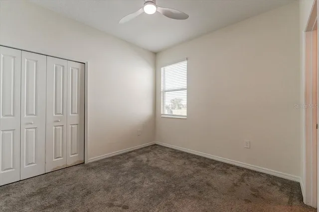 an empty room with windows and fan