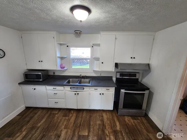 a kitchen with granite countertop white cabinets and black appliances
