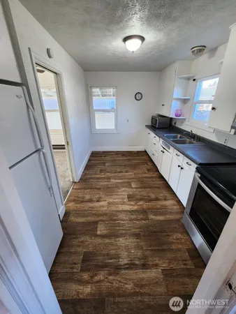a large white kitchen with sink stainless steel appliances and cabinets