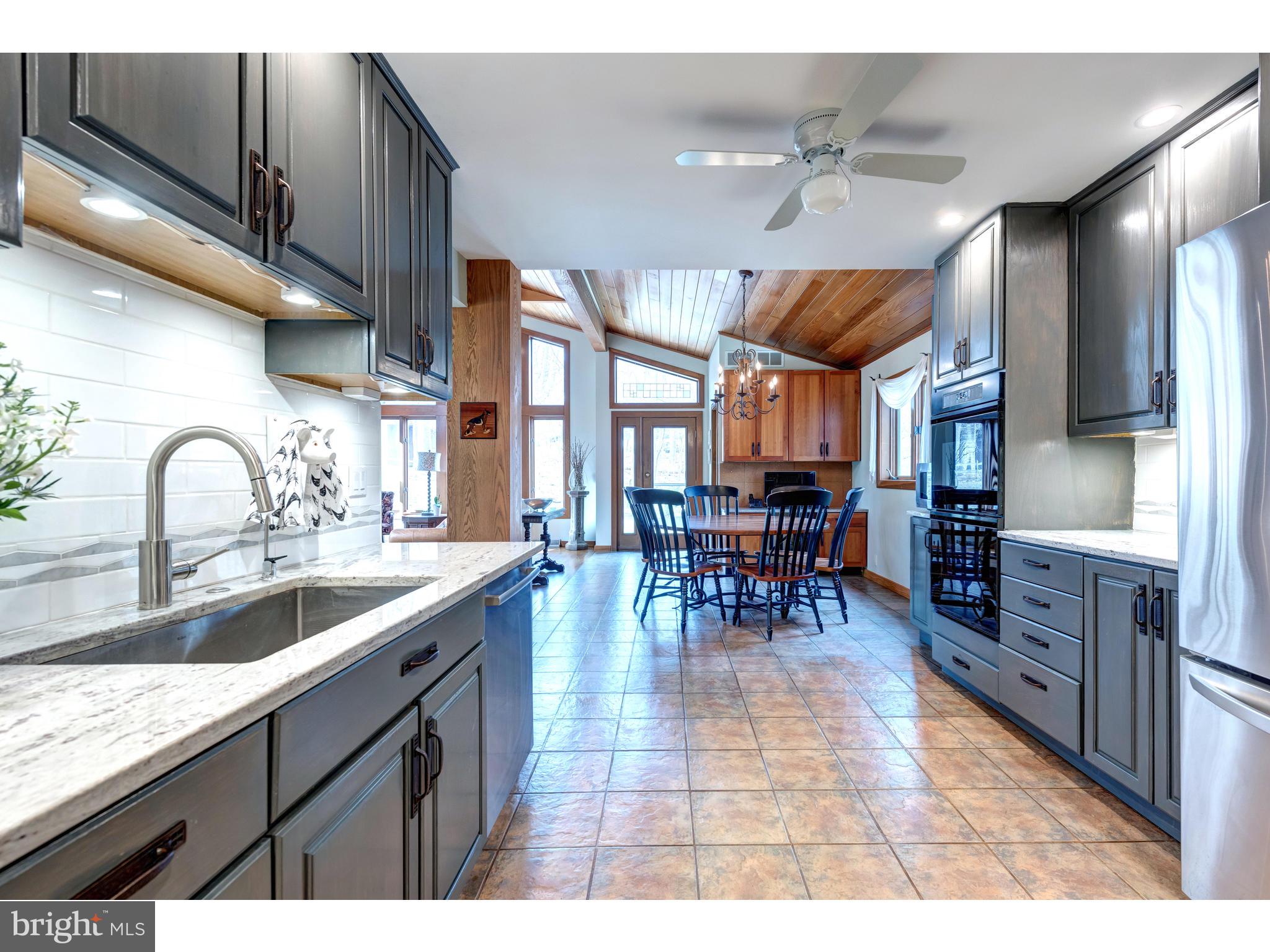 535 Upper Weadley Road Wayne, PA 19087 - Photo 27 of 44 a kitchen with stainless steel appliances granite countertop a sink a stove and a refrigerator with wooden floor