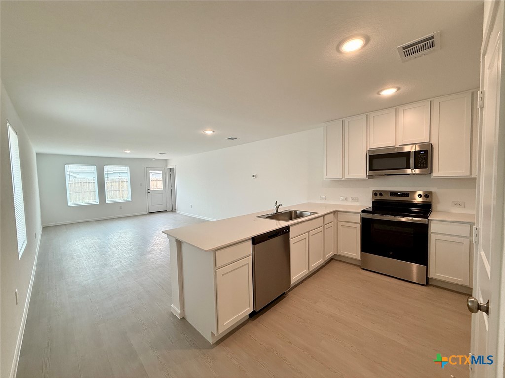 413 Moscato Road New Braunfels, TX 78130 - Photo 3 of 28 a kitchen with granite countertop a stove top oven and cabinets