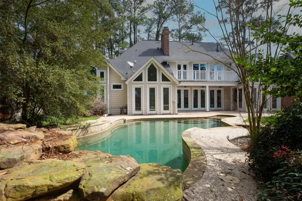an empty room with wooden floor chandelier and windows