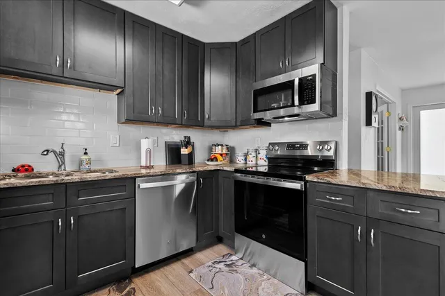a kitchen with stainless steel appliances granite countertop wooden cabinets a sink and dishwasher