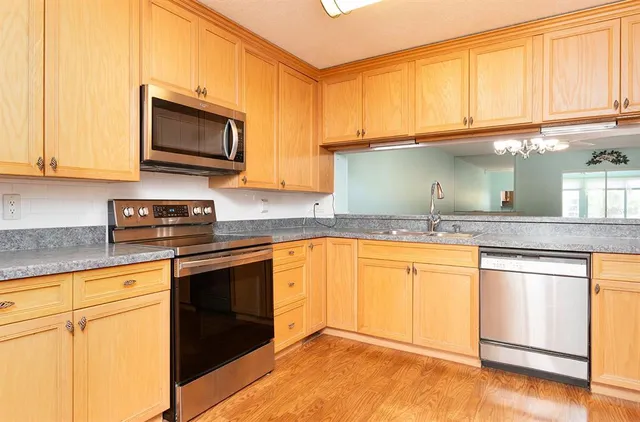 a kitchen with granite countertop a sink cabinets stainless steel appliances and a counter space