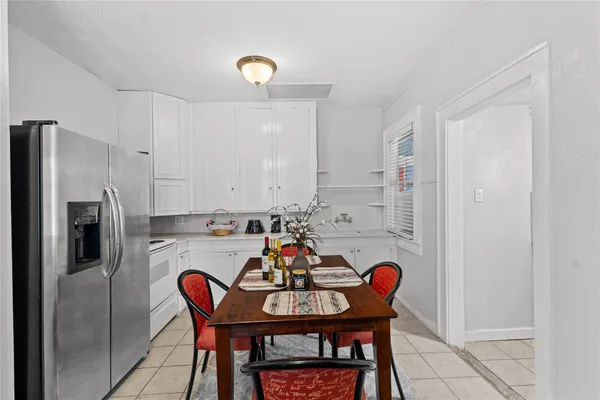 a kitchen with stainless steel appliances granite countertop a dining table chairs and a refrigerator