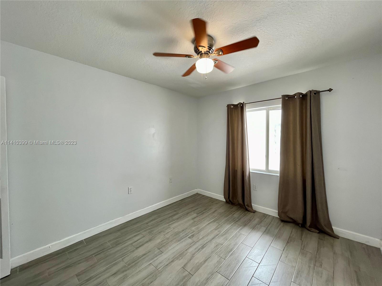 12030 Southwest 135th Terrace Miami, FL 33186 - Photo 16 of 27 an empty room with wooden floor fan and windows