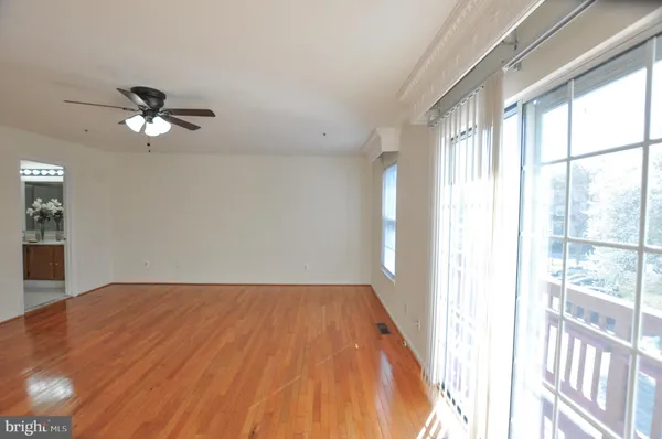a view of empty room with wooden floor and fan