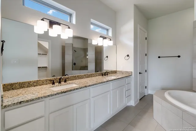 a bathroom with a granite countertop sink a large mirror and a bathtub