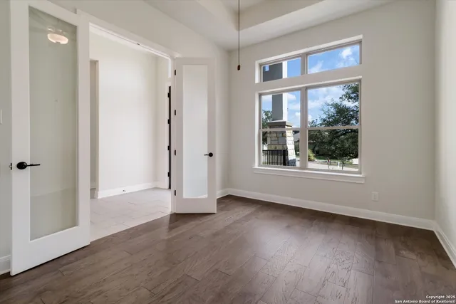 a view of an empty room with wooden floor and a window