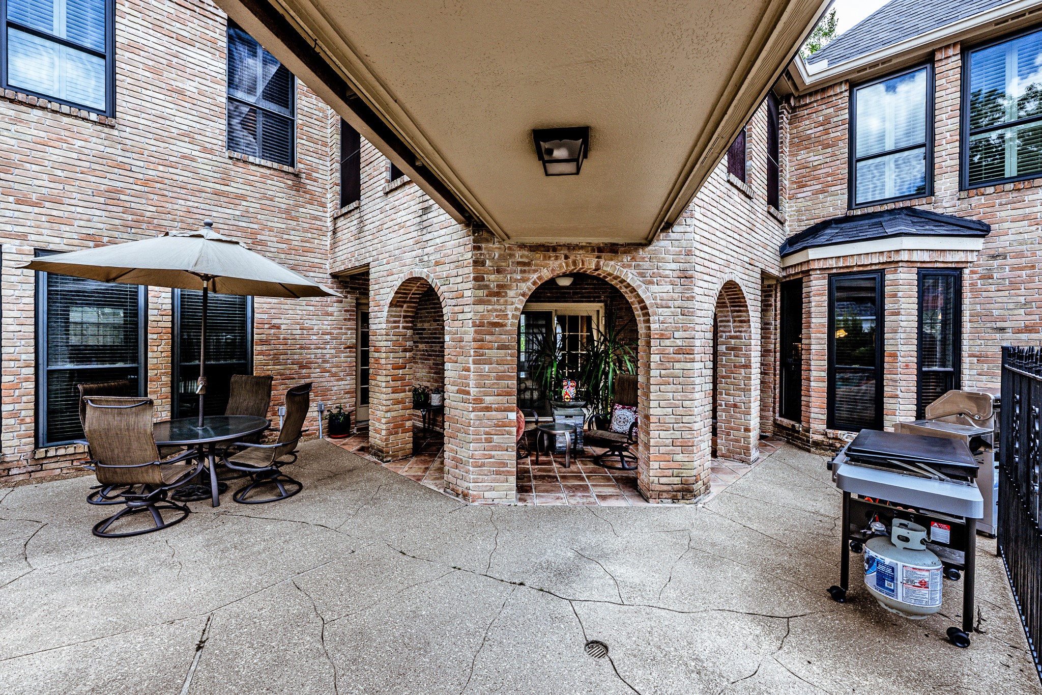 6047 Spring Creek Lane Spring, TX 77379 - Photo 38 of 50 Inside the backyard, a covered patio overlooks the pool and creates a natural extension of the home’s entertaining spaces. Arched brickwork and expansive shaded seating give the outdoor setting a relaxed, courtyard inspired feel designed for long Texas summers.