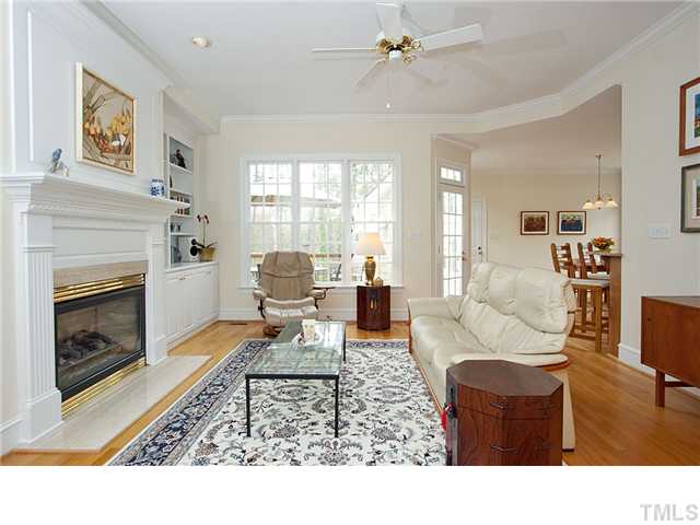 3312 Tall Tree Place Raleigh, NC 27607 - Photo 3 of 12 Sunlit family room that showcases fireplace, gleaming hardwoods, crown molding opening into kitchen and breakfast room. Beautiful deck and manicured grounds and privacy are part of this inviting ambiance.