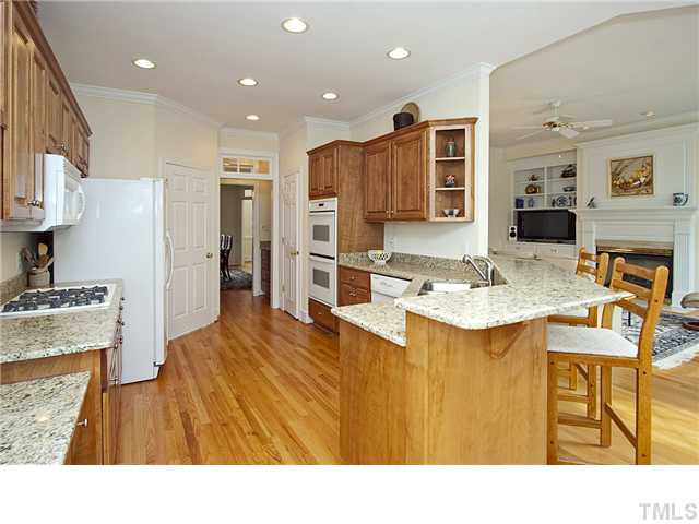 3312 Tall Tree Place Raleigh, NC 27607 - Photo 5 of 12 Sparkling open kitchen with new granite counter tops and backsplash, bar, stainless steel sink, double ovens, refrigerator, gas cooktop, new microwave, cherry cabinets, Butler's pantry with granite tops is between kitchen and elegant dining room.