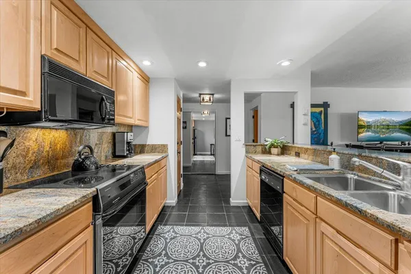 a kitchen with granite countertop stainless steel appliances a sink a counter top space and cabinets