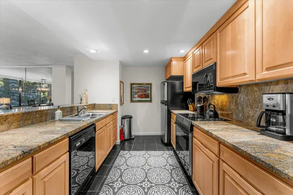 a kitchen with stainless steel appliances granite countertop a sink and a refrigerator