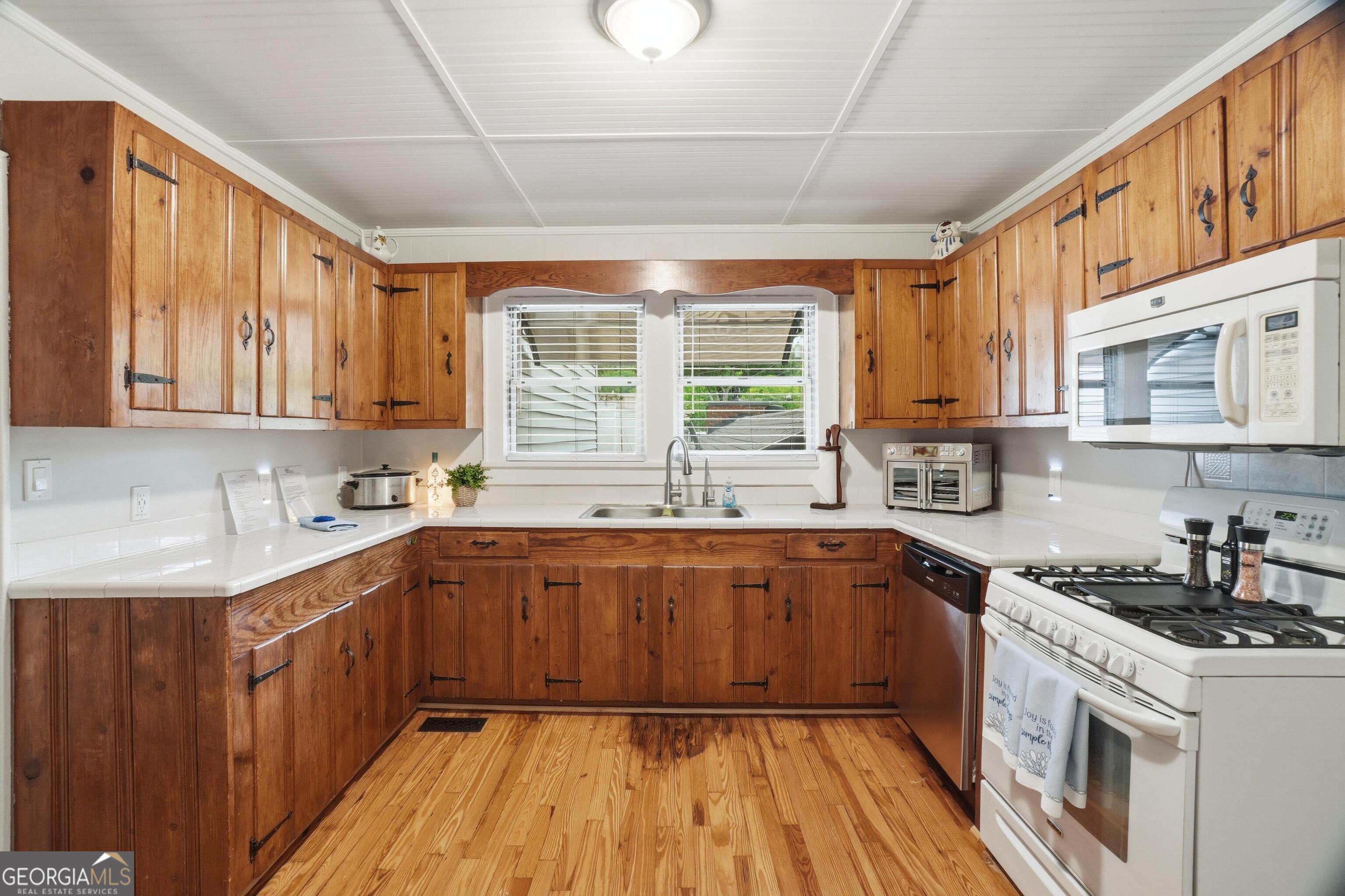 3022 Maple Road Southeast Lindale, GA 30147 - Photo 11 of 29 a kitchen with a sink wooden cabinets and white appliances