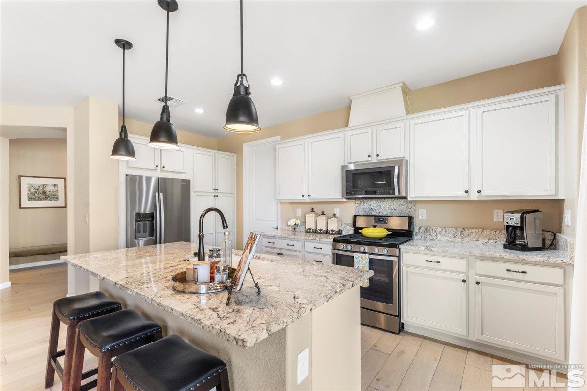 2315 Trakehner Lane Reno, NV 89521 - Photo 14 of 40 a kitchen with stainless steel appliances granite countertop a stove a sink a microwave a dining table and chairs